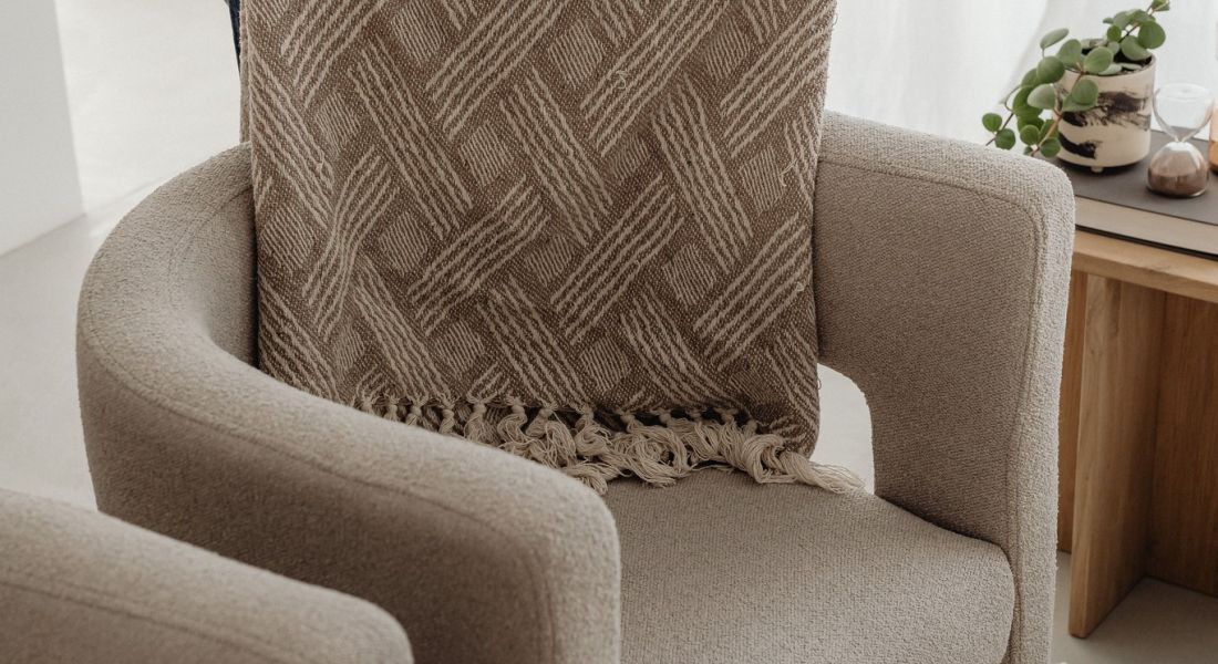 Woman folding a blanket over the back of a modern chair