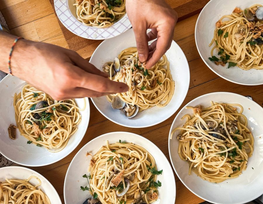 Modern restaurant interior with round hanging lights, tall ceilings, and black tables and chairs, with few people dining.