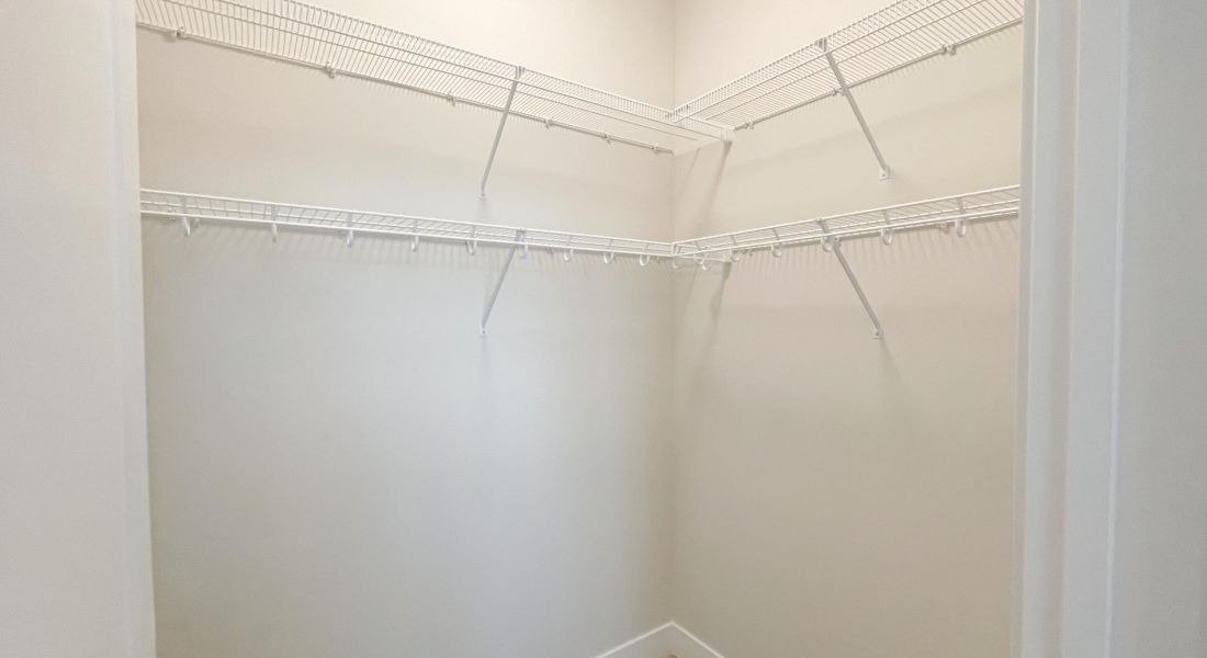 Empty walk-in closet with white walls and wire shelving on two sides.