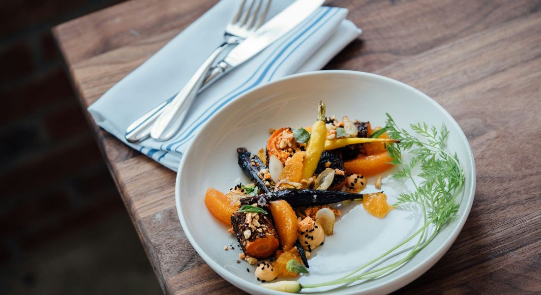 A plate of seafood pasta and an empty wine glass on a table, with a salad in the background.